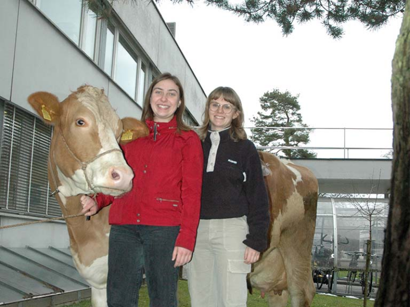 Foto von Lorine Droux (links) und Justine Maillard (rechts). Die beiden posieren mit einer Kuh.